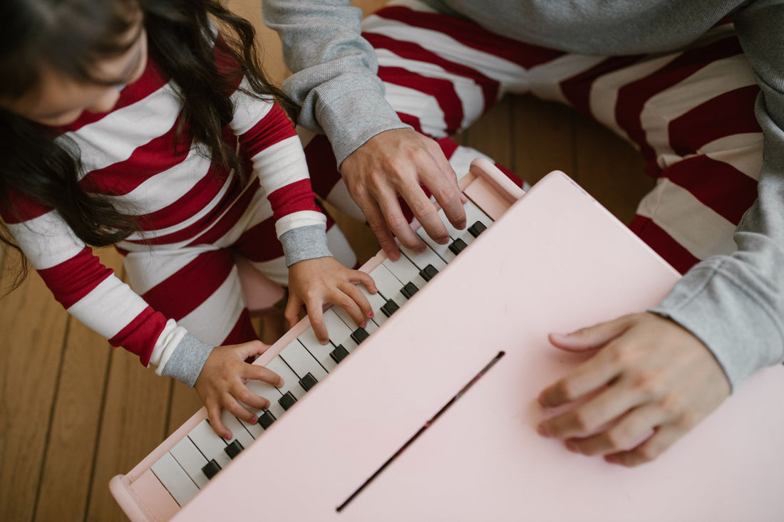 Parent and child playing a toy piano keyboard together