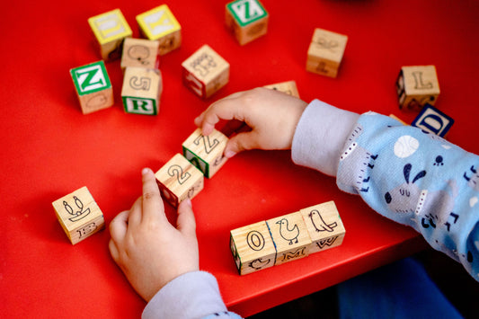 Child arranging wooden alphabet blocks on a table at home