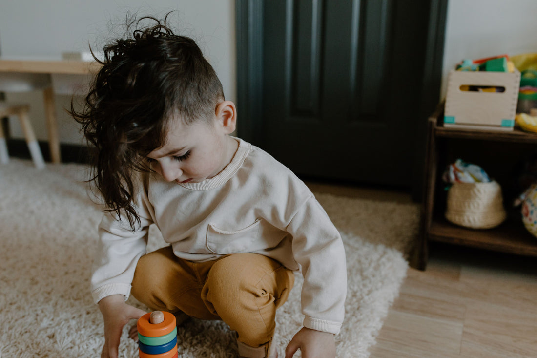 Toddler concentrating on a stacking toy on the floor at home