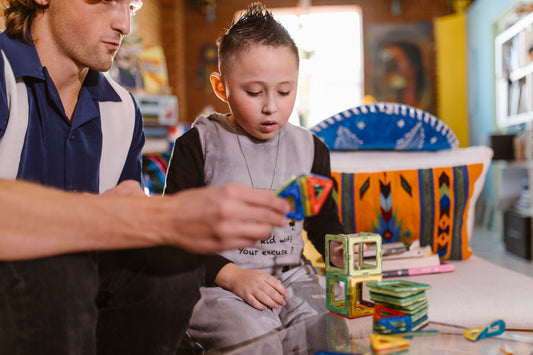Parent and child building a colorful magnetic tile structure together indoors