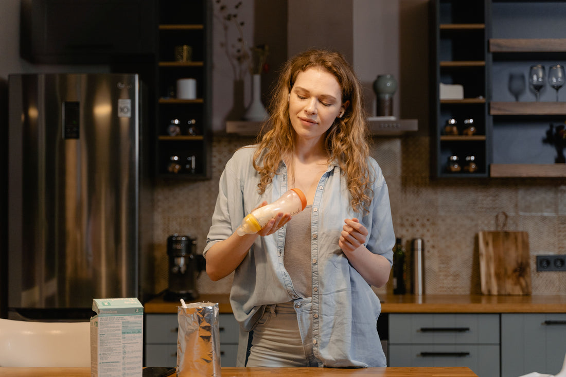 Parent organizing baby bottles at a bright kitchen counter