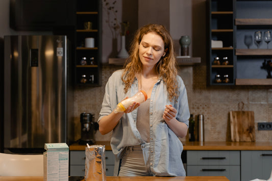 Parent organizing baby bottles at a bright kitchen counter