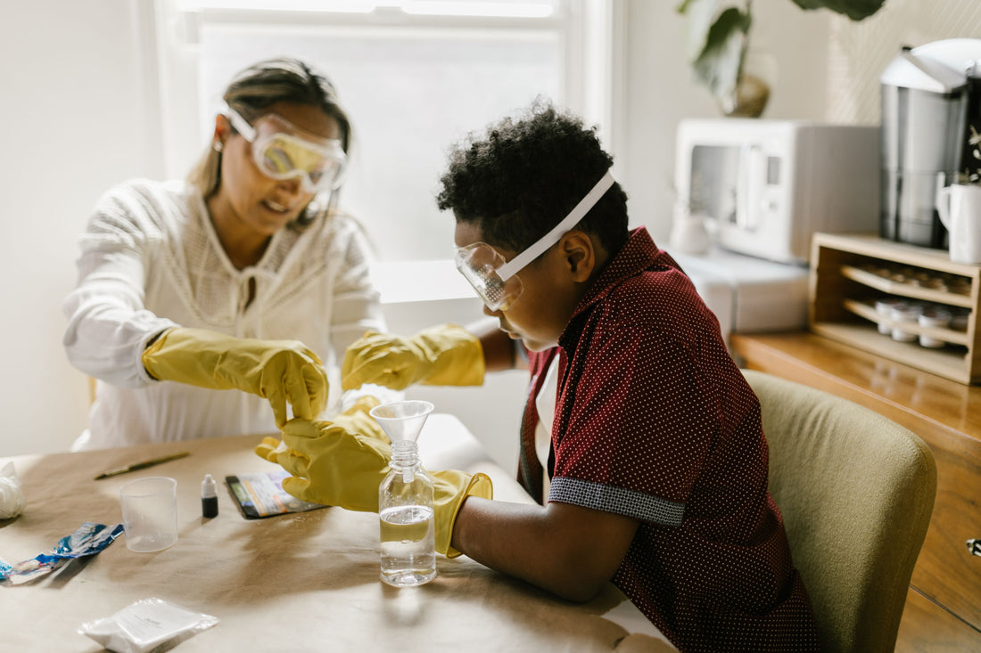 Parent and child wearing safety goggles doing a science experiment at the kitchen table