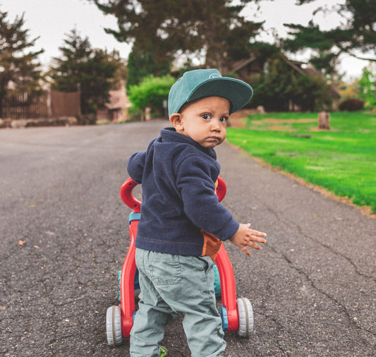 Toddler pushing a wheeled push toy while walking outdoors