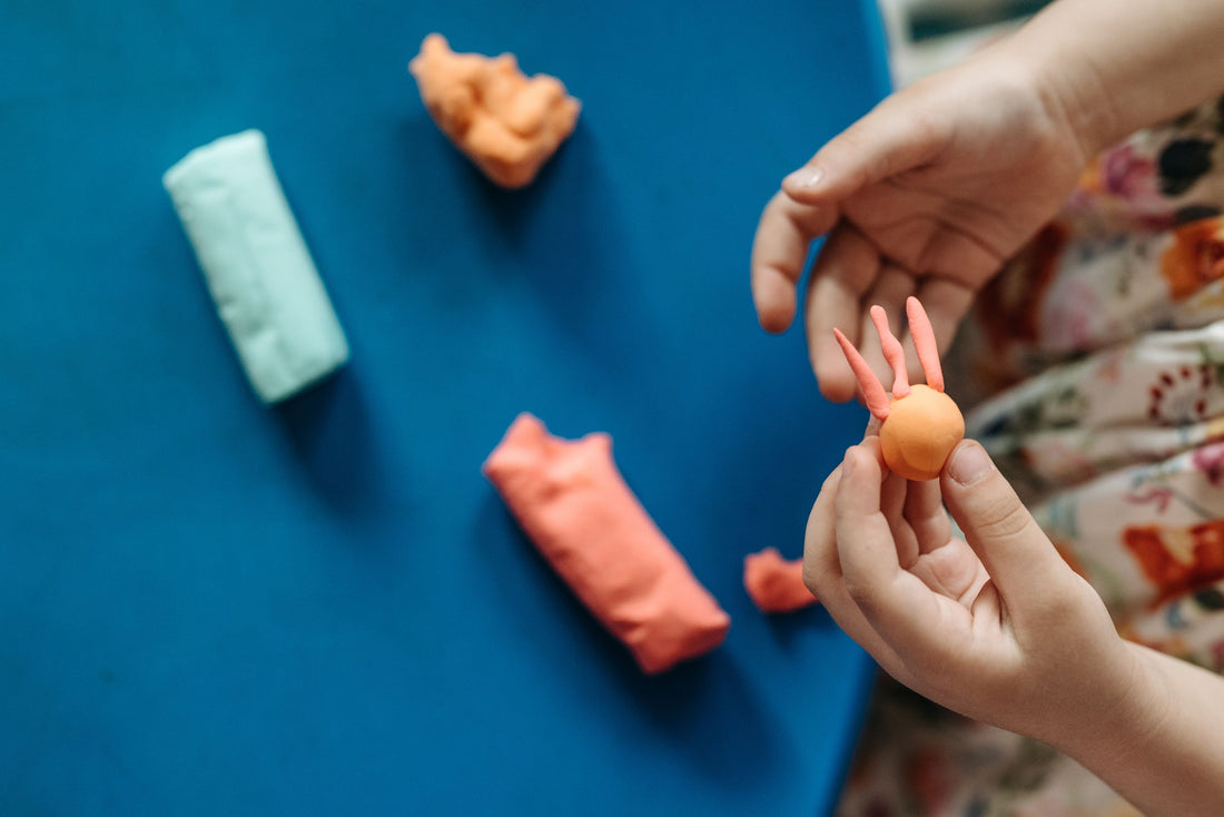 Child shaping colorful air-dry clay figures by hand