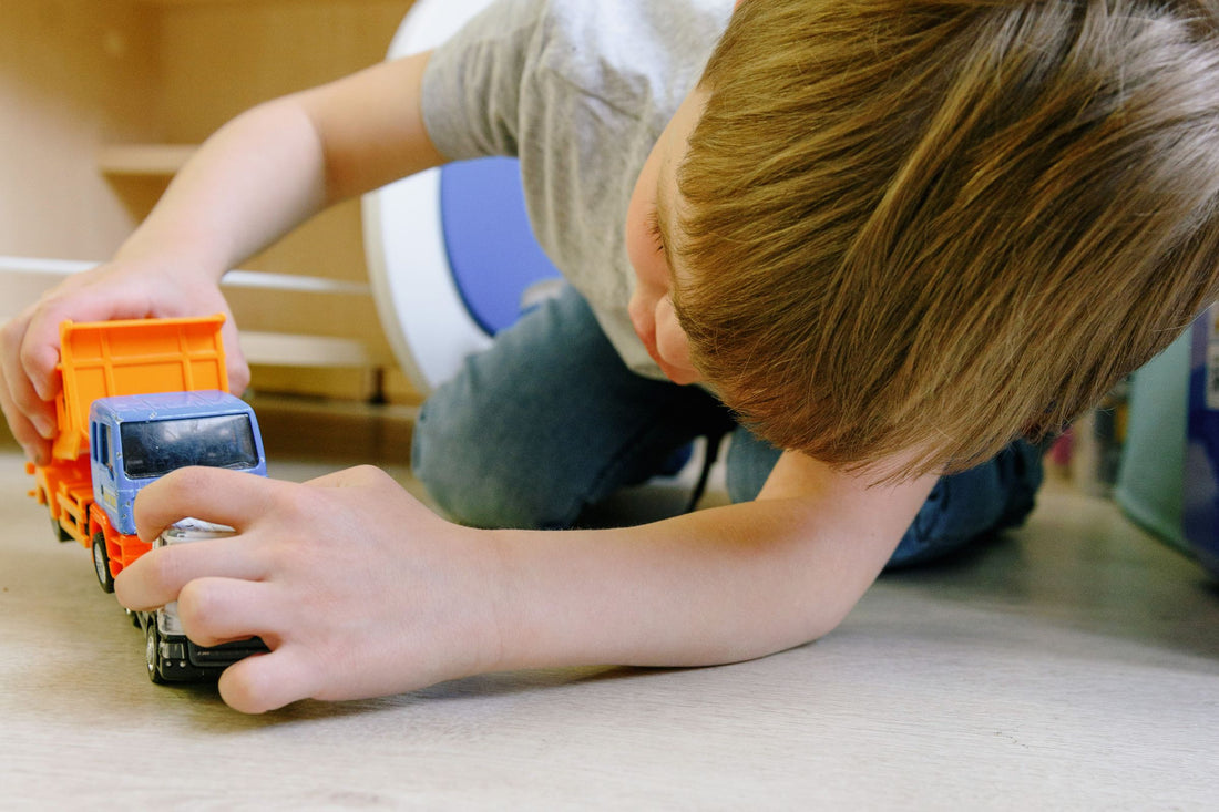Child playing with small toy trucks on the floor