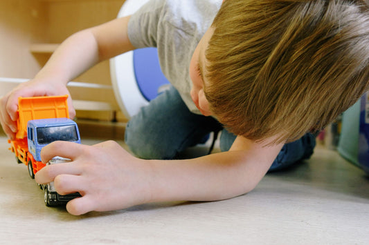 Child playing with small toy trucks on the floor