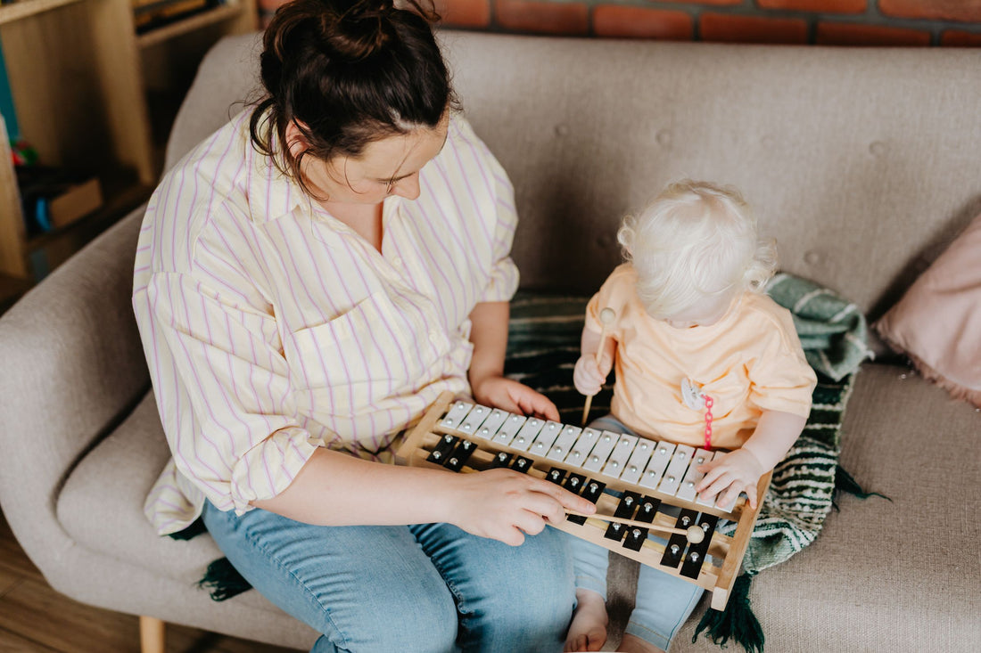 Parent and toddler playing a toy xylophone together at home
